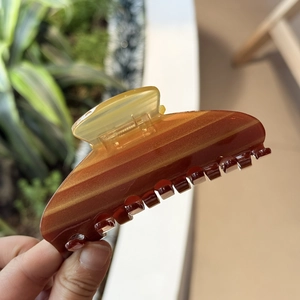 Detail shot of a large acetate hair claw with amber stripes and golden glitter particles