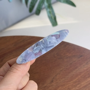 Détail de la barrette en acétate bleu avec motif marbré et finition polie élégante
