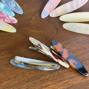Vue détaillée de dessus de barrettes en acétate aux motifs marbrés et écailles sur bois