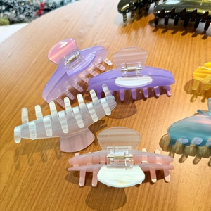 Detail shot of multi-colored acetate hair claws with marble texture on wooden background