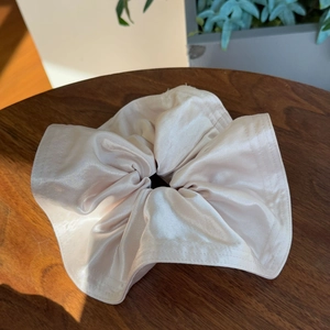 Elegant oversized champagne satin scrunchie with silk-like folds on a wooden background
