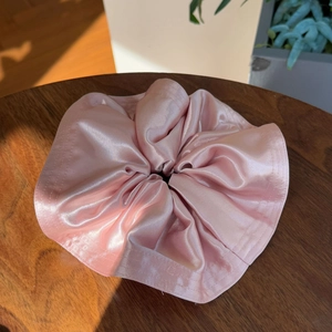 Elegant large pink satin hair scrunchie with silk luster on a vintage wooden table