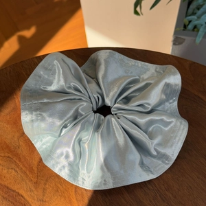 Lustrous light blue silk satin scrunchie with elegant pleats on a wooden table