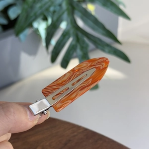 Elegant orange marble patterned hair clip with silver metal base in a lifestyle setting