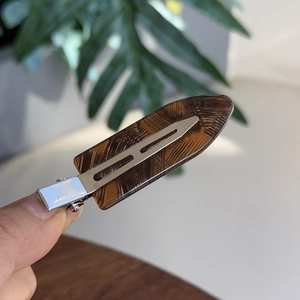 Detailed macro view of the tortoiseshell resin duckbill hair clip with silver metal parts