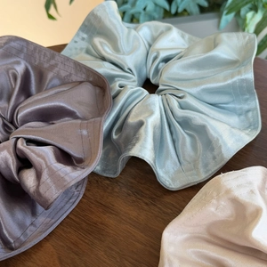 Close-up of oversized satin scrunchies in pastel colors showing silky fabric texture