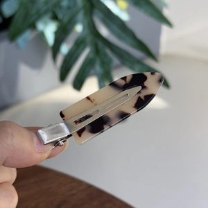 Close-up of tortoise shell pattern acetate hair clip with silver metal duckbill clip