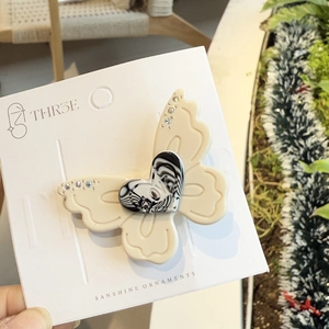 Detailed macro of a resin butterfly hair clip with marble heart and rhinestone accents