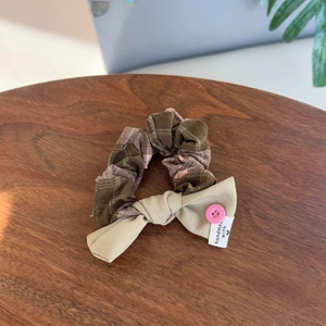 Detailed view of pink and brown plaid scrunchie with a handmade fabric bow and button