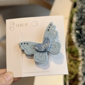 Elegant light blue butterfly hair clip with marble heart accent and sparkling rhinestones