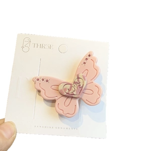 Pink acrylic butterfly hair clip with love heart detail on a white display card
