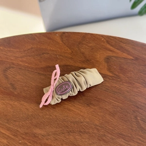 Detail of khaki pleated hair clip with pink bow and cute oval bead decoration