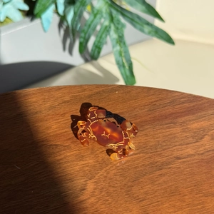 Detailed view of a unique crab-shaped cellulose acetate hair claw with amber texture