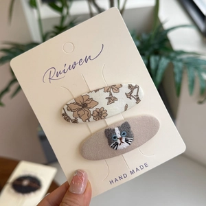 Haarspeldjesset van stof met bloemenprint en kattenborduurwerk op beige kaart