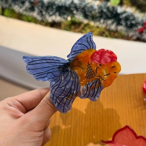 Détail d'une pince à cheveux en acétate en forme de poisson rouge aux nageoires bleues