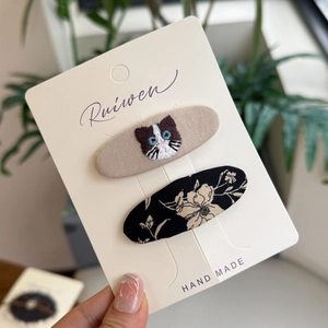Set haarspelden van stof met bloemenprint en geborduurde kat op kaart