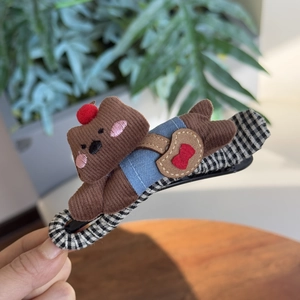 Détail d'une pince à cheveux petit chien en velours marron avec motifs à carreaux