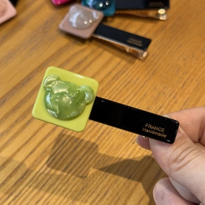 Detail of handmade acetate bear hair clip showing the green resin charm and black clamp