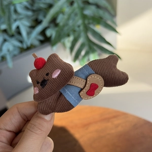 Détail d'une pince à cheveux ourson en velours côtelé marron avec cerise et sac coeur