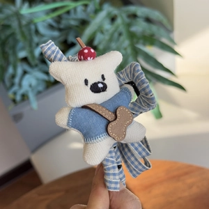 Détail d'un chouchou ours en peluche avec ruban à carreaux bleu et couture précise