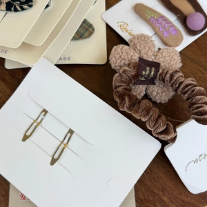 Detailopname van geborduurde bloem haarspeld en fluwelen scrunchie op merkkaarten