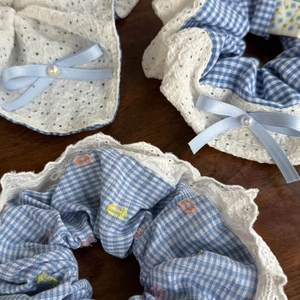 Close-up of blue plaid scrunchie with lace edge and elegant pearl center detail