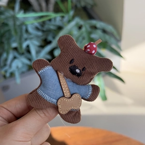 Détail de pince à cheveux chien en peluche avec tissu rayé et petite veste en jean bleu