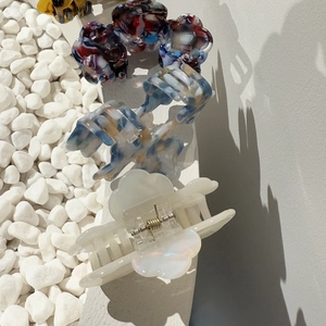Detail view of acetate star and flower hair clips on white stones in minimalist style