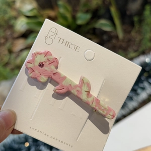 Sweet floral acetate hair clip with pink marble texture and crystal center on card