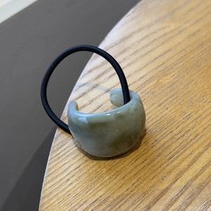 Fermaglio per capelli verde salvia effetto marmo con elastico nero su legno