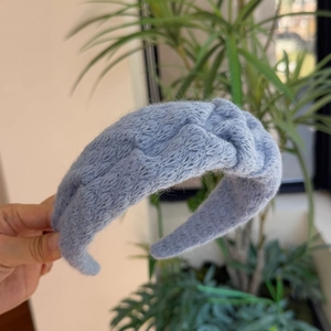 Detail van de zachte lichtblauwe gebreide hoofdband met pluizige textuur en knoop