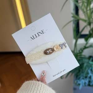 Détail de la barrette en tissu crème avec dentelle, perle en bois et nœud doux