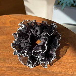 Detail of black lace scrunchie with white wave edges and delicate pleated organza texture