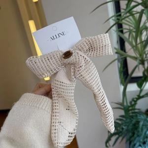 Détail d'un nœud papillon en dentelle beige avec bouton rétro tenu par un modèle