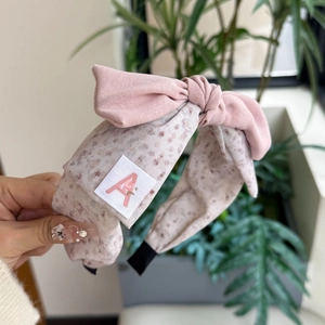 Detailaufnahme des rosa Haarreifs mit Schleife, Stoffstruktur und gewebtem A-Etikett