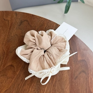 Détail de chouchou en lin kaki avec bords en dentelle et un petit nœud en ruban satiné