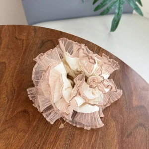 Détail d'un chouchou en lin beige avec broderie en dentelle sur table en bois