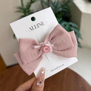 Detailaufnahme einer rosa karierten Haarschleife mit Spitze und dekorativem Knopf