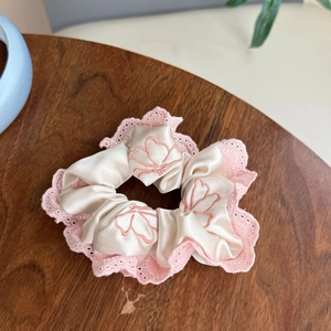 Elegante elastico in raso beige con pizzo rosa e ricami a farfalla su base di legno