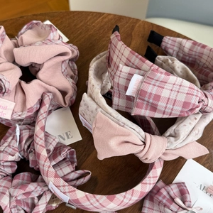 Haarschmuck-Set in Rosa-Karo mit Schleifenstirnband und Haargummi auf Holzgrundlage