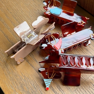Details von süßen Acryl-Dackel-Haarklammern mit Schalmuster auf einer Holzoberfläche