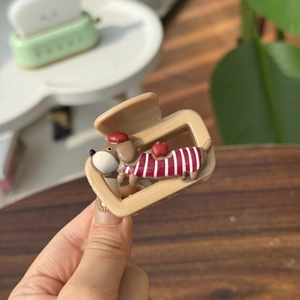 Close-up of cute sausage dog hair claw clip with red striped sweater detail