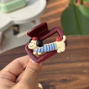 Detail of burgundy hair claw clip featuring a cute dachshund in striped sweater