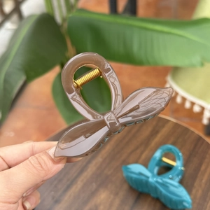 Elegant large bow hair claw clip in amber brown and navy blue, made of acrylic material