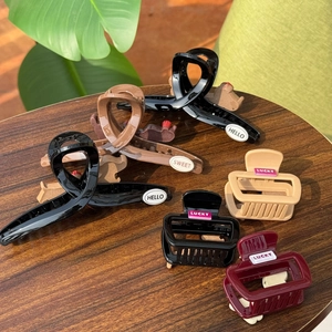 Detail of assorted hair claw clips with HELLO and LUCKY text on a wooden surface