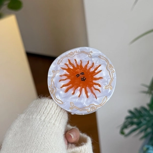 Vintage round hair claw with sun pattern and marble texture design held by hand