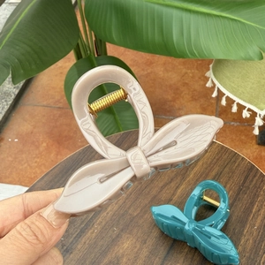 Close-up of elegant leaf-shaped hair claws in taupe and teal with gold metal springs