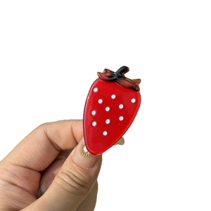 Pince à cheveux fraise brillante avec points blancs et feuilles vertes sur fond blanc