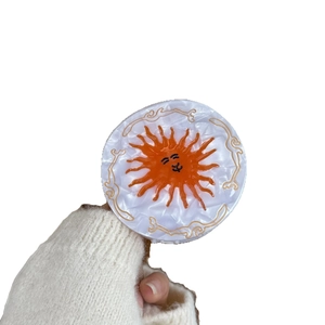 Retro round hair claw clip with orange sun pattern and golden embossed vintage borders
