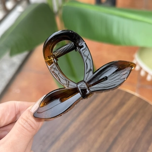 Detail of amber resin bow hair claw clip with glossy finish and metal spring